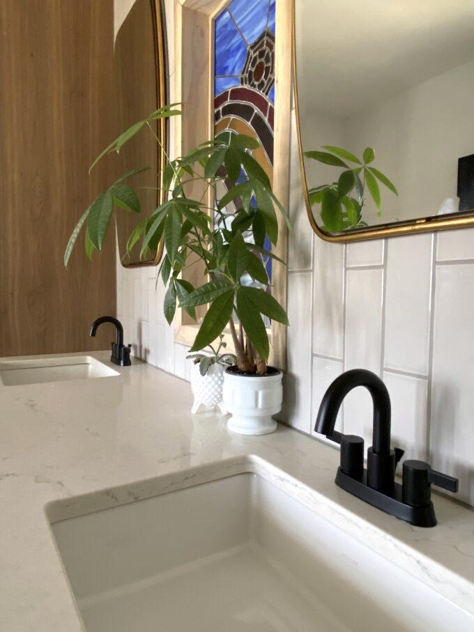 Quartz counter with twin sinks and faucets with vertical backsplash subway tile.